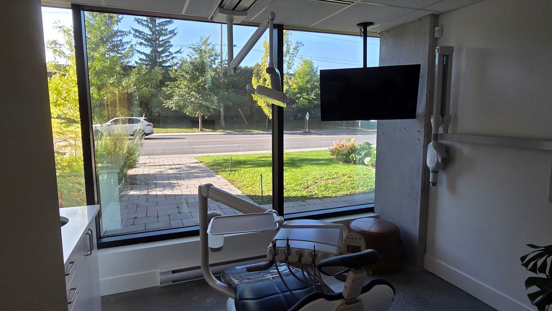 Vue depuis l'intérieur d'une salle de traitement : la grande fenêtre laisse voir la rue, le terrain et les arbres